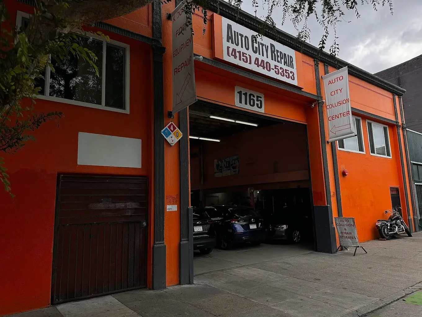 The orange Auto City Repair building on Folsom Street in San Francisco, with a collision center banner and an open service bay
